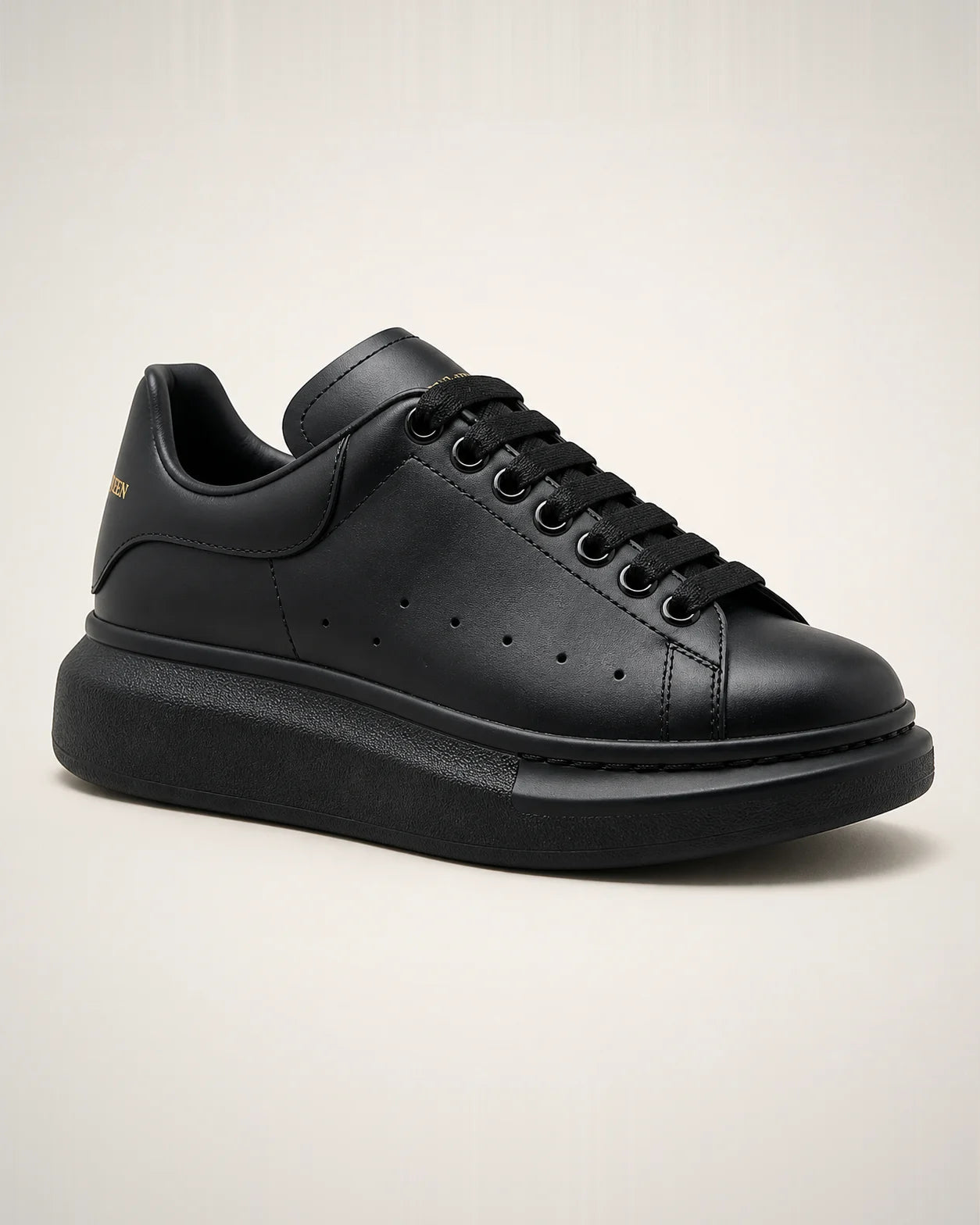 Oversized monocromático negro en piel lisa con branding dorado y plataforma de gran volumen.
