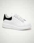 Oversized blanco en piel lisa con talonera negra, branding dorado y plataforma blanca gruesa.