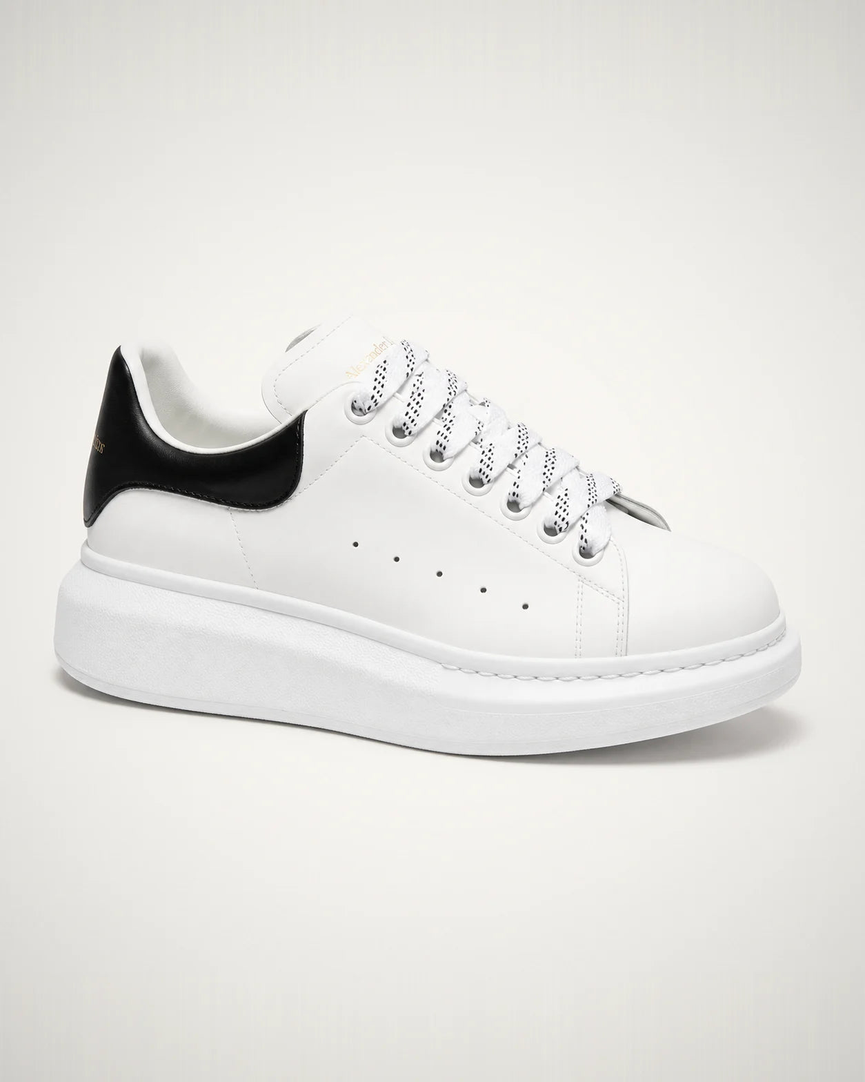 Oversized blanco en piel lisa con talonera negra, branding dorado y plataforma blanca gruesa.