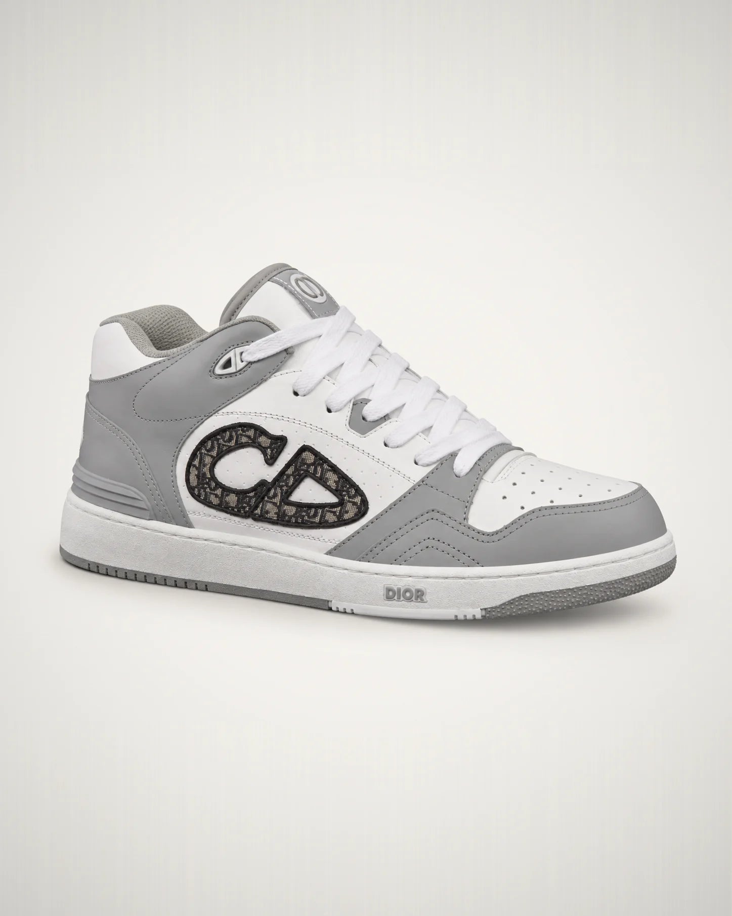 B57 gris y blanco con emblema CD Oblique lateral, paneles de piel y suela cupsole de perfil basquetbolero.