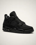 Jordan 4 totalmente negro con nubuck, jaulas laterales, alas moldeadas y unidad Air visible.