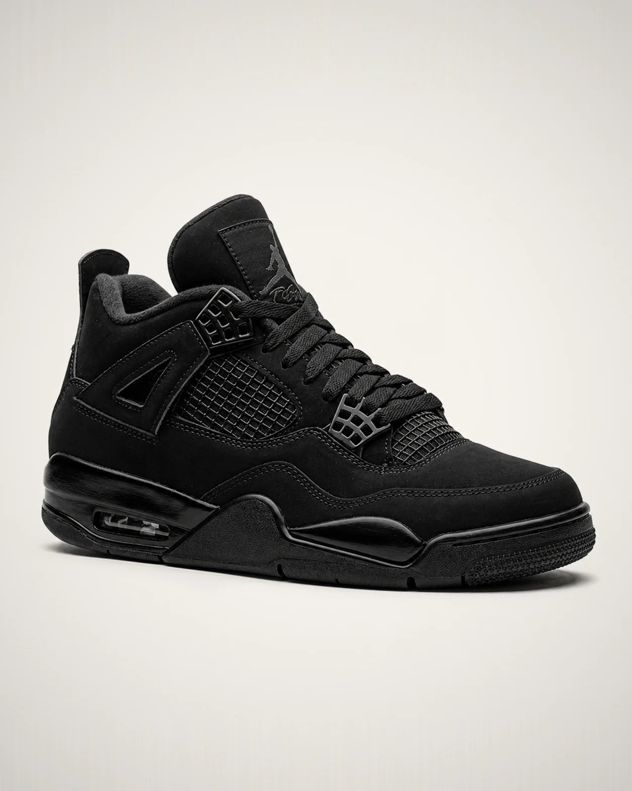 Jordan 4 totalmente negro con nubuck, jaulas laterales, alas moldeadas y unidad Air visible.