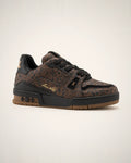 LV Trainer café con textura gráfica oscura, piel negra, detalles dorados y outsole color goma.