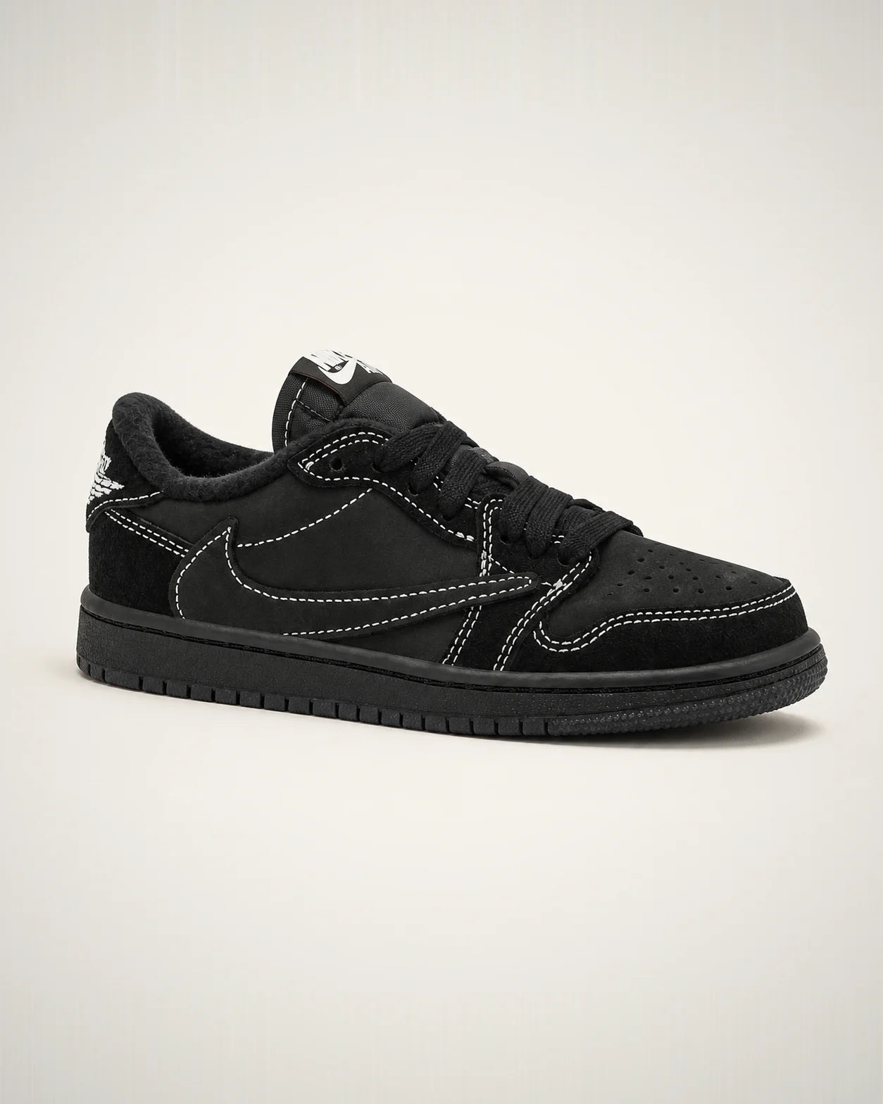 Jordan 1 Low negro con Swoosh invertido, gamuza tonal y costuras blancas de alto contraste.